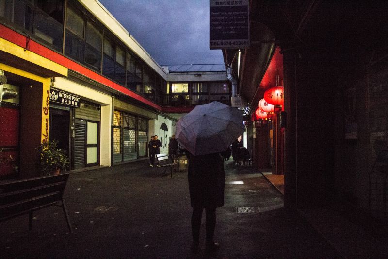 A dark street, a person with an umbrella